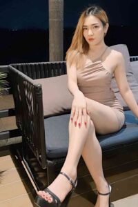 Woman in beige dress sitting on outdoor furniture.