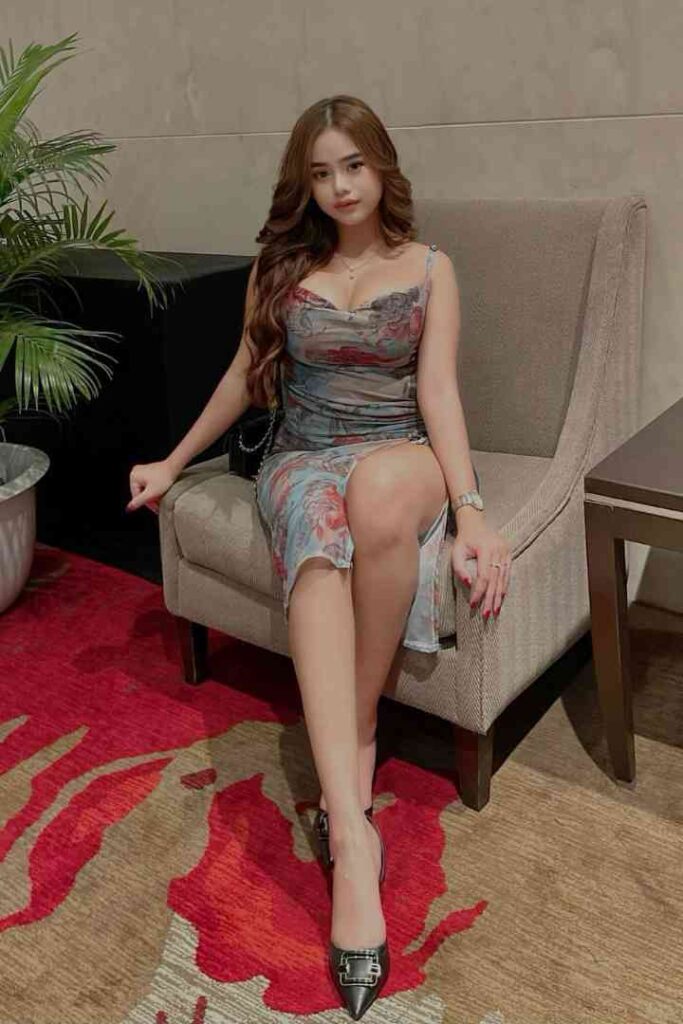 Woman in floral dress sitting on a chair.