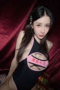 Woman in black cutout bodysuit with pink lettering.